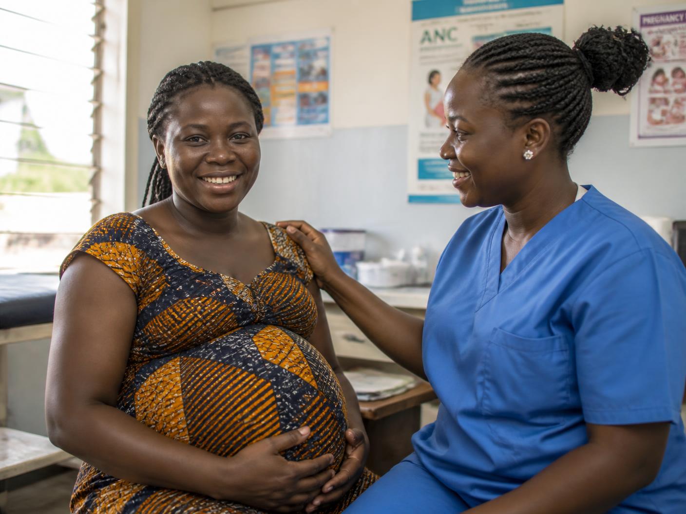 Une femme enceinte souriante avec une infirmière lors d'une consultation prénatale